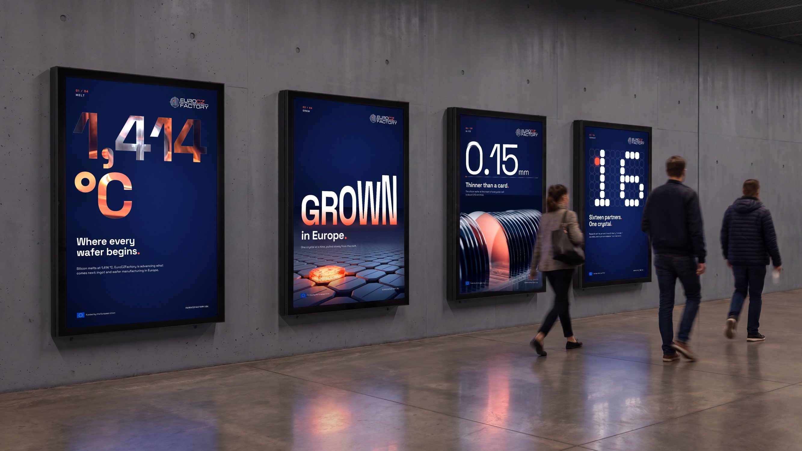 The four typographic posters in backlit frames along a metro passage, commuters walking past.