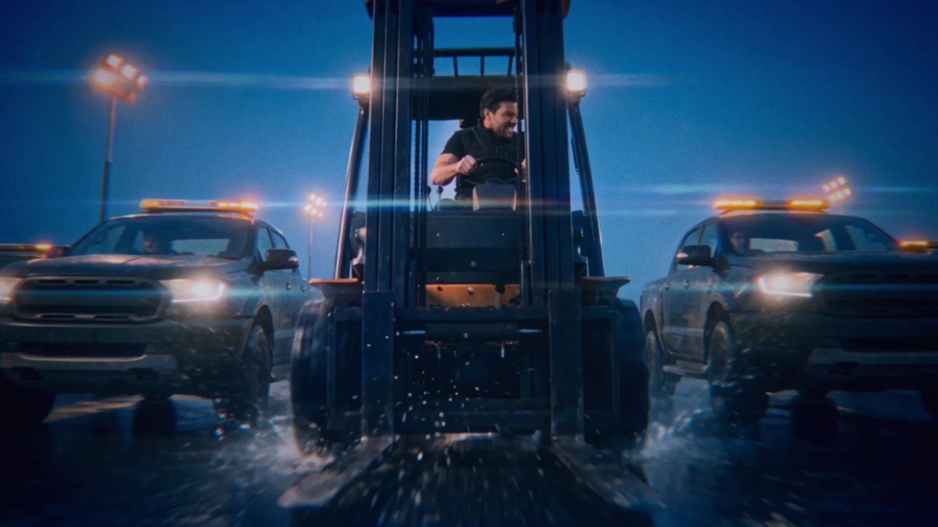 The thief drives a forklift through the wet loading yard between pursuing security vehicles